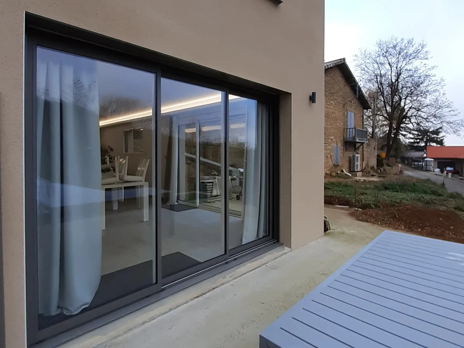 Extérieur d'habitation moderne avec grande baie vitrée coulissante ouverte donnant sur l'intérieur