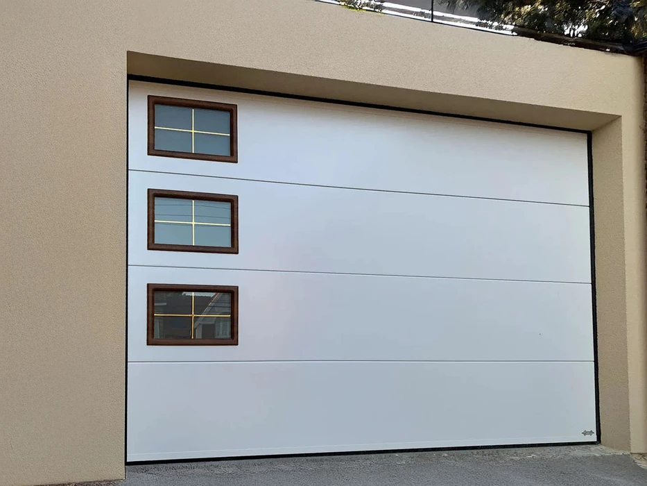 Porte de garage sectionnelle blanche avec trois fenêtres rectangulaires à carreaux, montants en bois foncé