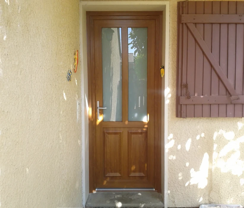 Extérieur d'une habitation avec grande baie vitrée coulissante à cadre blanc PVC installée dans mur crépi beige