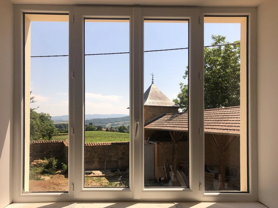 Façade extérieure d'une construction en bois avec volet roulant électrique partiellement fermé sur une fenêtre