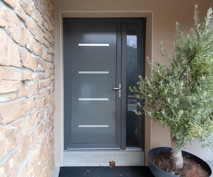Entrée extérieure d'une habitation avec porte blanche vitrée à six carreaux dans la partie haute et deux panneaux pleins en partie basse