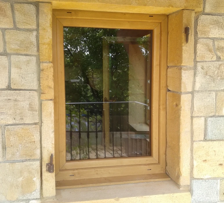 Extérieur d'une habitation avec fenêtre moderne à cadre anthracite installée dans mur crépi beige